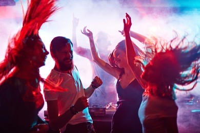 group of energetic friends dancing in night club