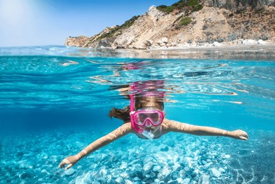 underwater split view of a girl snorkeling in the turquoise, mediterranean sea during summer holiday time