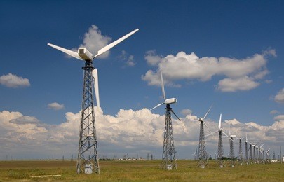 wind farm against rural landscape. blue sky with clouds are in the background.