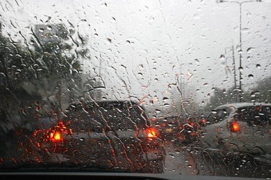 road view through car window with rain drops, driving in rain.