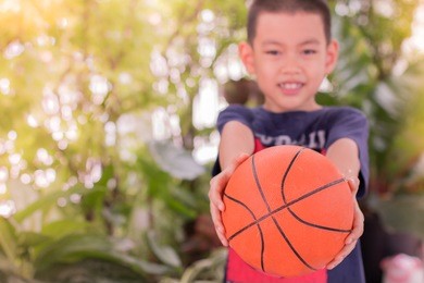 happy asian boy holding basketball