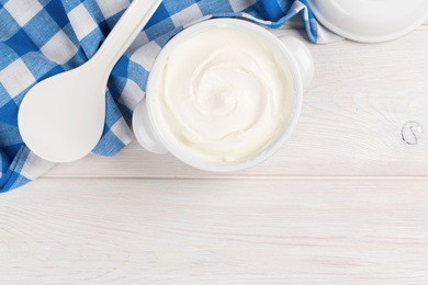 sour cream in a bowl on wooden table. top view with copy space