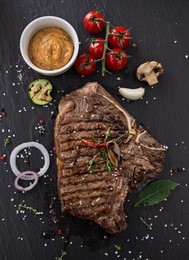 beef t-bone steak on black stone table, close-up.