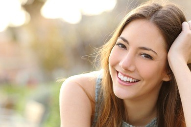 woman smiling with perfect smile and white teeth in a park and looking at camera