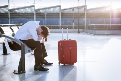 depressed traveler waiting at airport after flights delays and cancellations