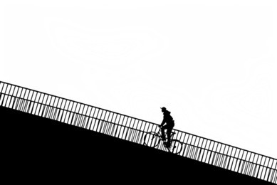 silhouette of a man on a rise with bicycle in black and white