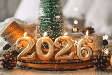 decorative candles and a small christmas tree create a cozy scene celebrating the new year in winter 2026