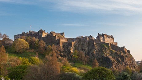 beautiful image of edinburgh castle in scotland. photographed in may with blossoming park in foreground and during sunset 'golden hour', which is known for its perfect light