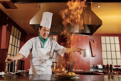 kitchen hell. japanese cook frying a vegetarian meal in burning flame of spirit on restaurant kitchen