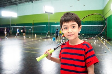 little boy taking badminton racket in training class at the gym