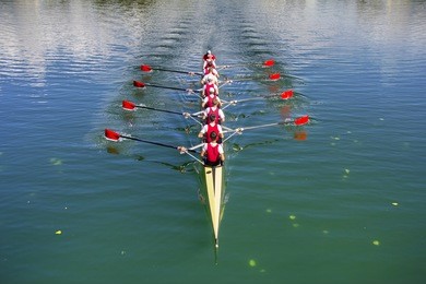 boat coxed eight rowers rowing on the blue lake