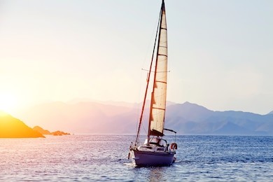 beautiful racing yacht in the mediterranean sea with blue sky and mountains on background, sailing boat at gold colorful sunset