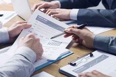business professionals working together at office desk, hands close up pointing out financial data on a report