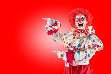 funny clown pointing at blank template copy spase for advertising, posters, greetings, invitations. entertainer as joker in a suit and wig, with clown whiteface makeup.