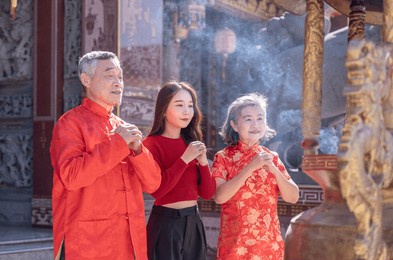 asian family in cheongsam pray and worship together at incense burner in chinese temple,chinese new year concept