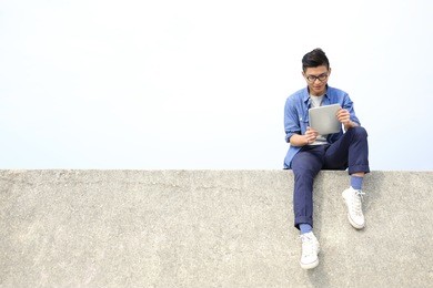 happy college student man using digital tablet pc and sit, asian male