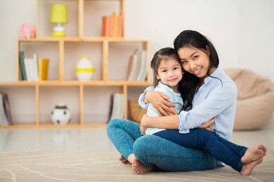 portrait of happy young woman and her daughter hugging and looking at the camera