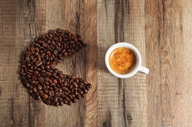 coffee espresso. a cup of coffee costs on a wooden table. next to a cup of coffee beans. creative 