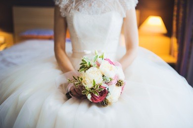 beautiful bouquet of different colors in the hands of the bride in a white dress