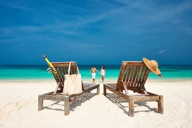 couple in white walking on a tropical beach at maldives