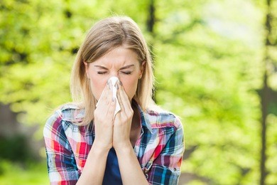 woman with with allergy symptom blowing nose