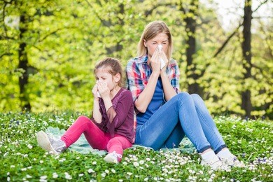 two people with allergy symptom blowing nose
