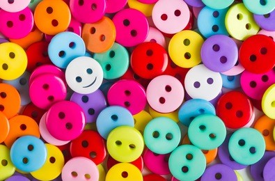 bright multicolored buttons of red, yellow, blue, orange, pink, purple, color, among them the white button - smiley stands out among other, top view, 
background