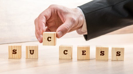 close up hand of a businessman arranging small wooden blocks on the table for success concept.