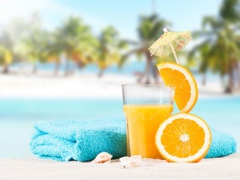 fresh orange juice, fruits on sand with blue sky background, summer concept 