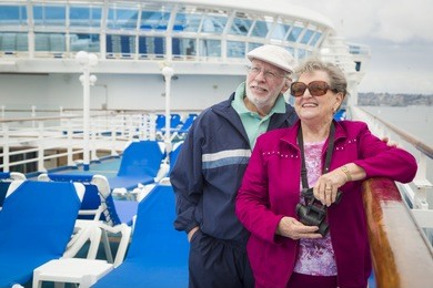 happy senior couple enjoying the view from deck of a luxury passenger cruise ship.