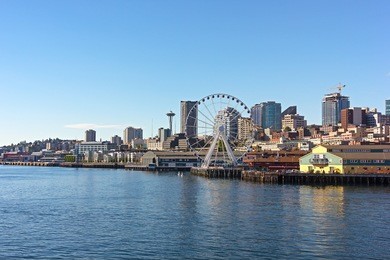 a view on seattle downtown from the waters of puget sound. piers, skyscrapers and ferris wheel in seattle city before sunset.