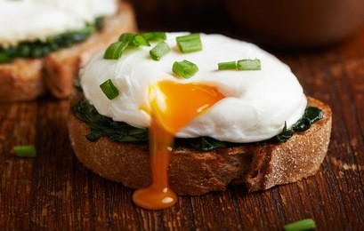 poached egg on a piece of bread with spinach on the wooden table