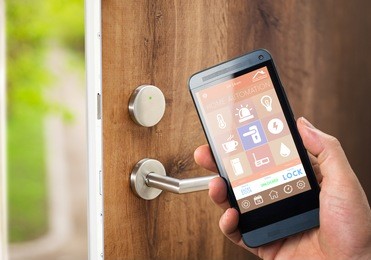 smart house, home automation, device with app icons. man uses his smartphone with smarthome security app to unlock the door of his house.