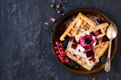 traditional belgian waffles with ice cream and berry fruit sauce in the plate,selective focus and blank space
