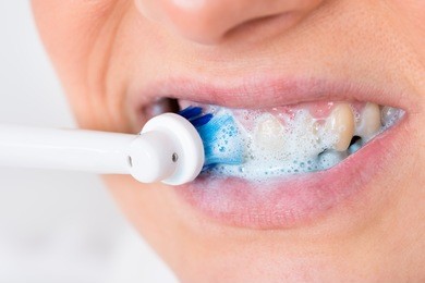 close-up of a person brushing teeth using electric toothbrush