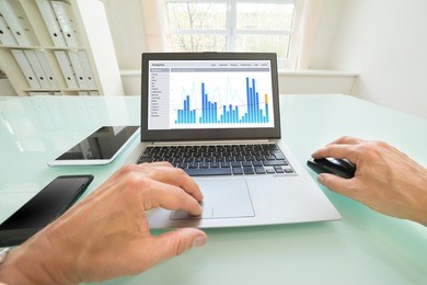 close-up of a person analyzing graph on laptop in office