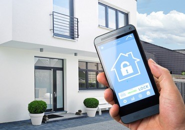smart house, home automation, device with app icons. man uses his smartphone with smarthome security app to unlock the door of his house.