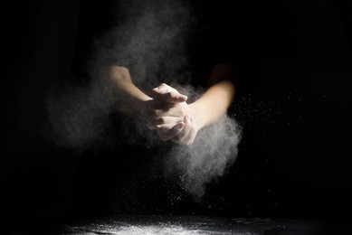 chef hand clap and white flour on black background