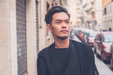young handsome asian model dressed in black tunic posing in the city streets