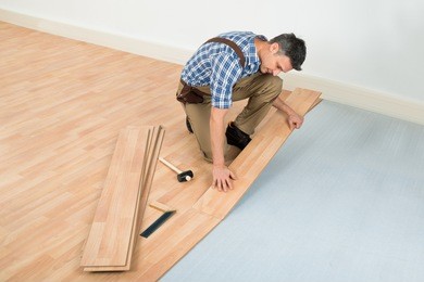 carpenter installing new laminated wooden floor at home