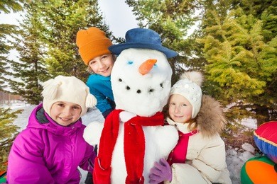 close-up view of children sitting close to snowman
