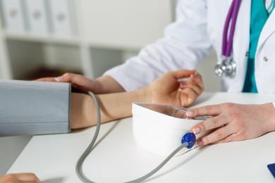 female medicine doctor measuring blood pressure to patient. patient communicates with physician doctor having medical examination. medical concept. hand of doctor and patient while pressure measuring