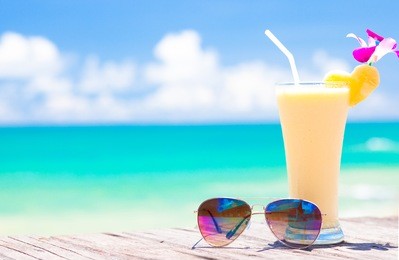 picture of fresh banana and pineapple juice and sunglasses on tropical beach