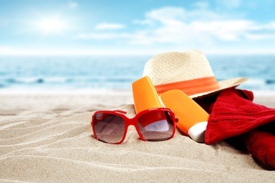 hat towel and red sunglasses on sand with suntan 