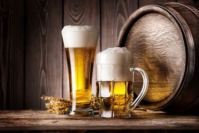 mug and a glass of light beer with ears of barley and wooden barrel
