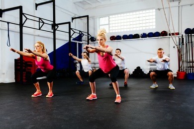 group of young people training squats at gym class.