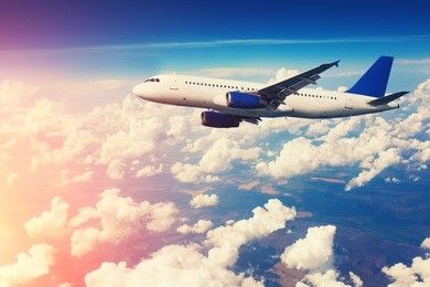 commercial airliner flying above clouds with blue sky in background. vintage toning, sun flare