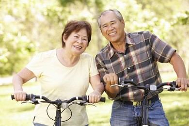 senior asian couple riding bikes in park