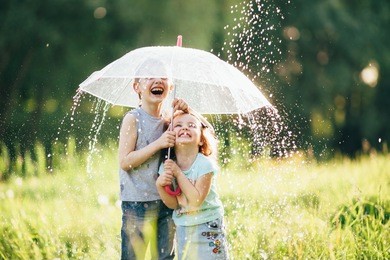 happy kids playing outdoor in raining spring park. shallow depth of field,focus on children or raindrops