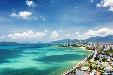 beautiful view on nha trang and nha trang bay of south china sea with magic colors of water on blue sky background in khanh hoa province, vietnam. nha trang is a popular tourist destination of asia.